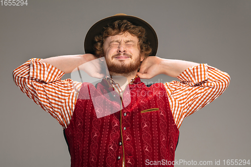 Image of Happy smiling man dressed in traditional Austrian or Bavarian costume gesturing isolated on grey studio background