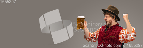 Image of Happy smiling man dressed in traditional Austrian or Bavarian costume gesturing isolated on grey studio background