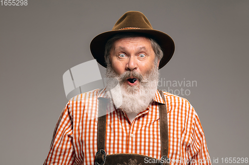 Image of Happy senior man dressed in traditional Austrian or Bavarian costume gesturing isolated on grey studio background