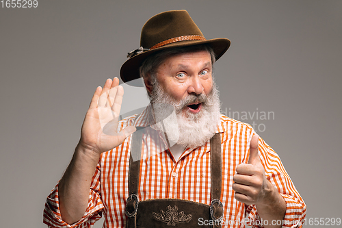 Image of Happy senior man dressed in traditional Austrian or Bavarian costume gesturing isolated on grey studio background