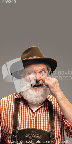 Image of Happy senior man dressed in traditional Austrian or Bavarian costume gesturing isolated on grey studio background