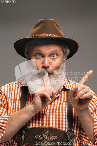 Image of Happy senior man dressed in traditional Austrian or Bavarian costume gesturing isolated on grey studio background
