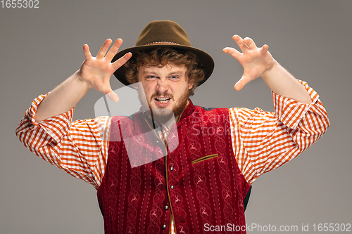 Image of Happy smiling man dressed in traditional Austrian or Bavarian costume gesturing isolated on grey studio background