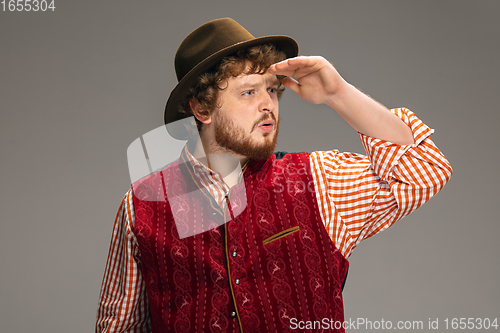 Image of Happy smiling man dressed in traditional Austrian or Bavarian costume gesturing isolated on grey studio background