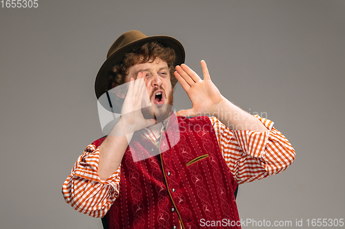 Image of Happy smiling man dressed in traditional Austrian or Bavarian costume gesturing isolated on grey studio background