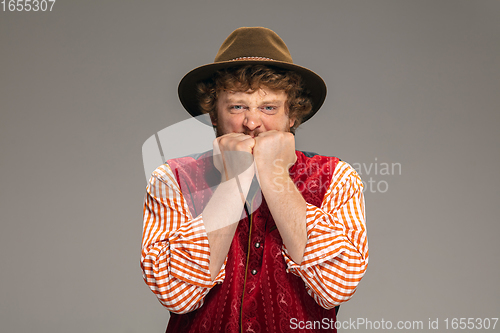 Image of Happy smiling man dressed in traditional Austrian or Bavarian costume gesturing isolated on grey studio background