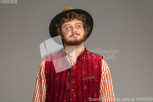 Image of Happy smiling man dressed in traditional Austrian or Bavarian costume gesturing isolated on grey studio background