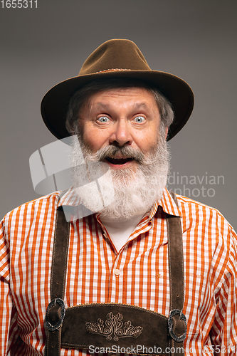 Image of Happy senior man dressed in traditional Austrian or Bavarian costume gesturing isolated on grey studio background