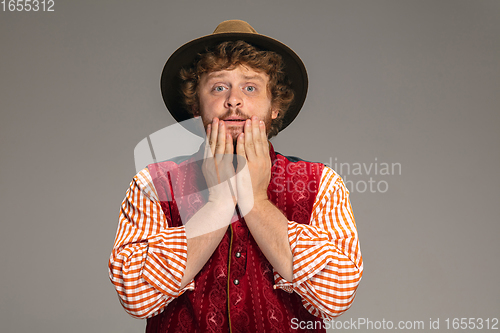 Image of Happy smiling man dressed in traditional Austrian or Bavarian costume gesturing isolated on grey studio background