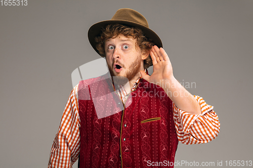 Image of Happy smiling man dressed in traditional Austrian or Bavarian costume gesturing isolated on grey studio background