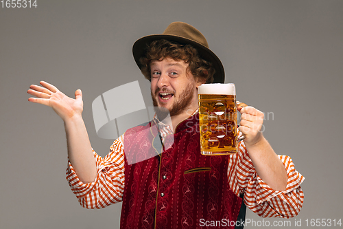 Image of Happy smiling man dressed in traditional Austrian or Bavarian costume gesturing isolated on grey studio background