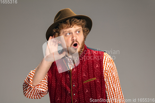 Image of Happy smiling man dressed in traditional Austrian or Bavarian costume gesturing isolated on grey studio background