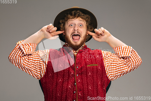 Image of Happy smiling man dressed in traditional Austrian or Bavarian costume gesturing isolated on grey studio background