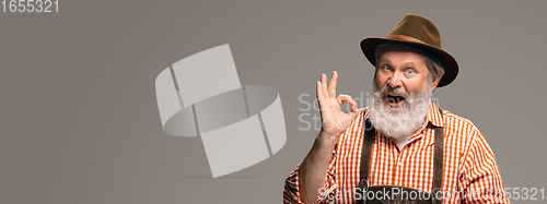 Image of Happy senior man dressed in traditional Austrian or Bavarian costume gesturing isolated on grey studio background