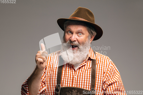 Image of Happy senior man dressed in traditional Austrian or Bavarian costume gesturing isolated on grey studio background