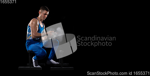 Image of Muscular male gymnast training in gym, flexible and active. Caucasian fit guy, athlete in blue sportswear isolated on black