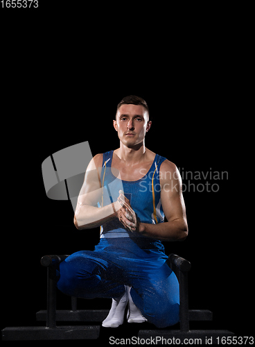 Image of Muscular male gymnast training in gym, flexible and active. Caucasian fit guy, athlete in blue sportswear isolated on black