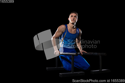 Image of Muscular male gymnast training in gym, flexible and active. Caucasian fit guy, athlete in blue sportswear isolated on black