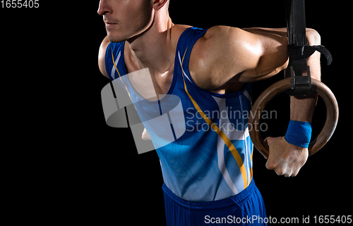 Image of Muscular male gymnast training in gym, flexible and active. Caucasian fit guy, athlete in blue sportswear isolated on black