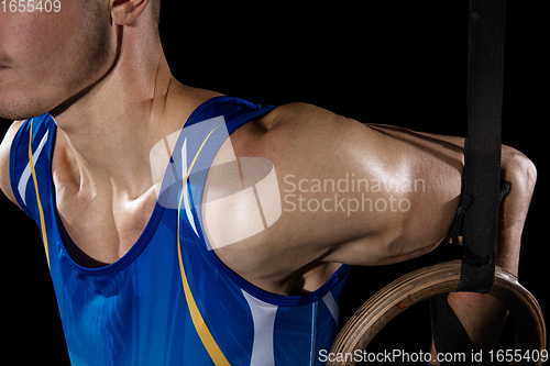 Image of Muscular male gymnast training in gym, flexible and active. Caucasian fit guy, athlete in blue sportswear isolated on black