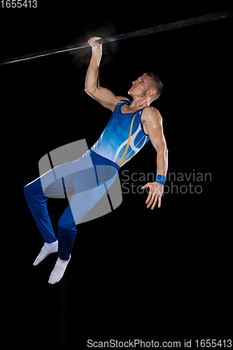 Image of Muscular male gymnast training in gym, flexible and active. Caucasian fit guy, athlete in blue sportswear isolated on black