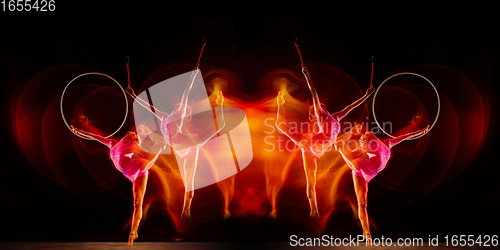 Image of Little flexible girl isolated on black studio background. Fire flames, reflection, strobe light effect