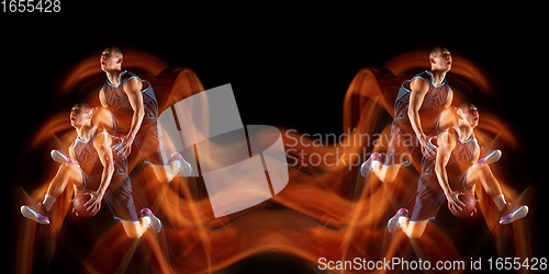 Image of Young purposeful basketball player training in action isolated on black background with fire flames. Mirror, strobe light effect, reflection