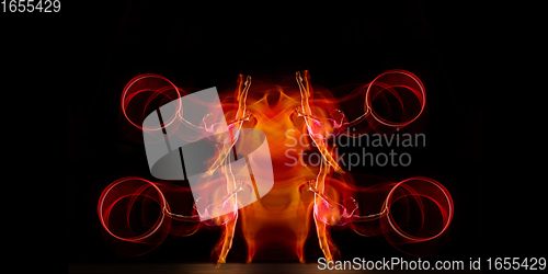 Image of Little flexible girl isolated on black studio background. Fire flames, reflection, strobe light effect