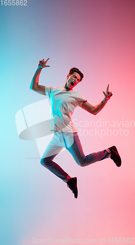 Image of Young caucasian man\'s portrait on gradient blue-pink studio background in neon light