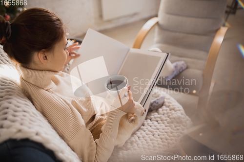 Image of Young woman enjoying her domestic life. Home comfort, winter and holidays time