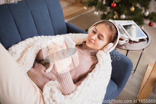 Image of Young woman enjoying her domestic life. Home comfort, winter and holidays time