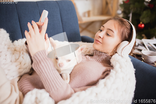 Image of Young woman enjoying her domestic life. Home comfort, winter and holidays time