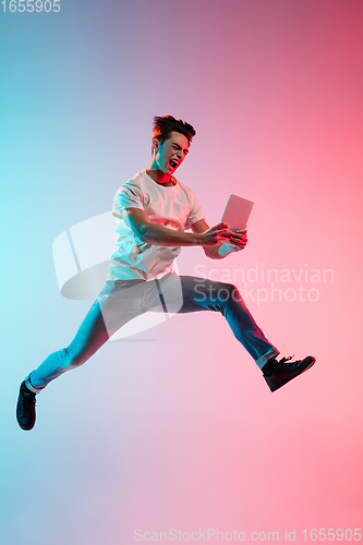 Image of Young caucasian man\'s portrait on gradient blue-pink studio background in neon light