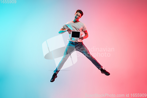 Image of Young caucasian man\'s portrait on gradient blue-pink studio background in neon light