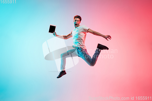 Image of Young caucasian man\'s portrait on gradient blue-pink studio background in neon light