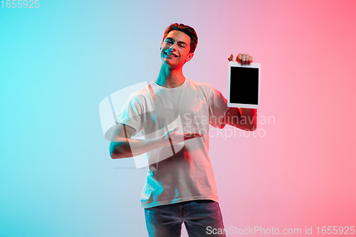Image of Young caucasian man\'s portrait on gradient blue-pink studio background in neon light