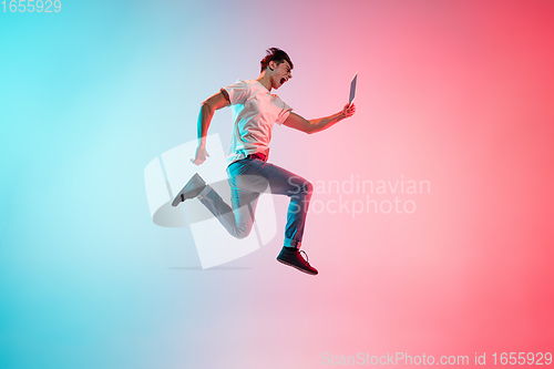 Image of Young caucasian man\'s portrait on gradient blue-pink studio background in neon light