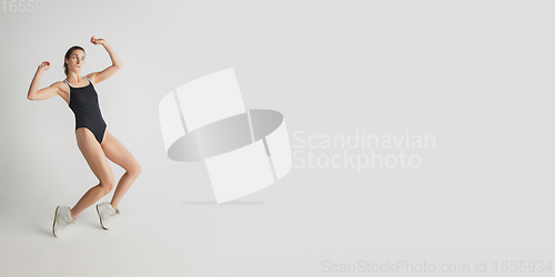 Image of Beautiful young woman\'s portrait isolated on grey studio background. Having fun, happy, full length