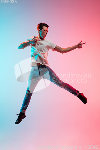 Image of Young caucasian man\'s portrait on gradient blue-pink studio background in neon light