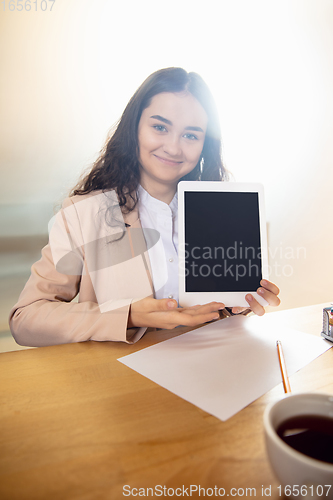 Image of Young woman talking, working during videoconference with colleagues at home office