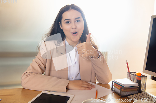 Image of Young woman talking, working during videoconference with colleagues at home office