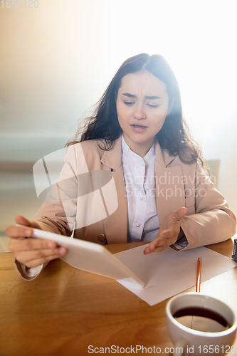 Image of Young woman talking, working during videoconference with colleagues at home office