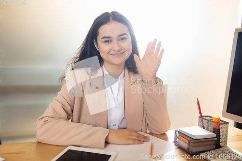 Image of Young woman talking, working during videoconference with colleagues at home office