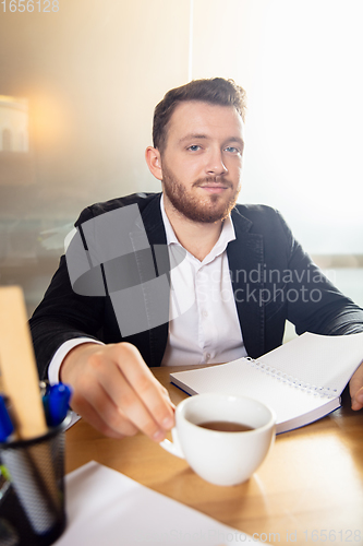 Image of Young man talking, working during videoconference with colleagues at home office