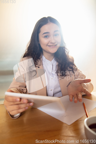 Image of Young woman talking, working during videoconference with colleagues at home office