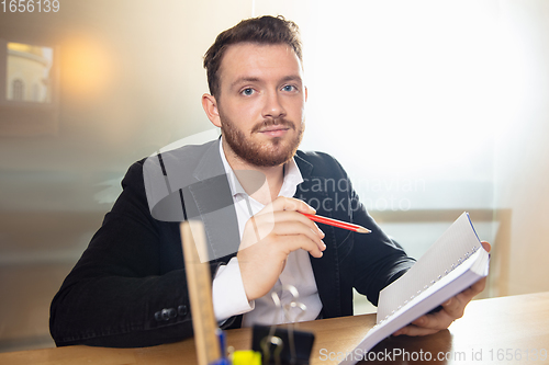 Image of Young man talking, working during videoconference with colleagues at home office