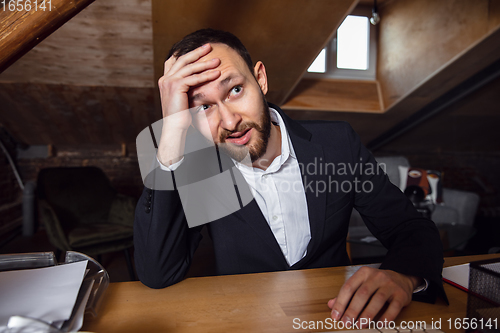 Image of Young man talking, working during videoconference with colleagues at home office