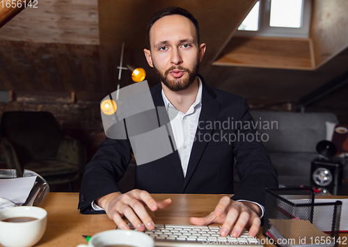 Image of Young man talking, working during videoconference with colleagues at home office