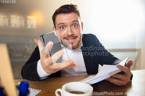 Image of Young man talking, working during videoconference with colleagues at home office