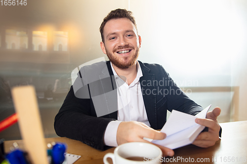 Image of Young man talking, working during videoconference with colleagues at home office